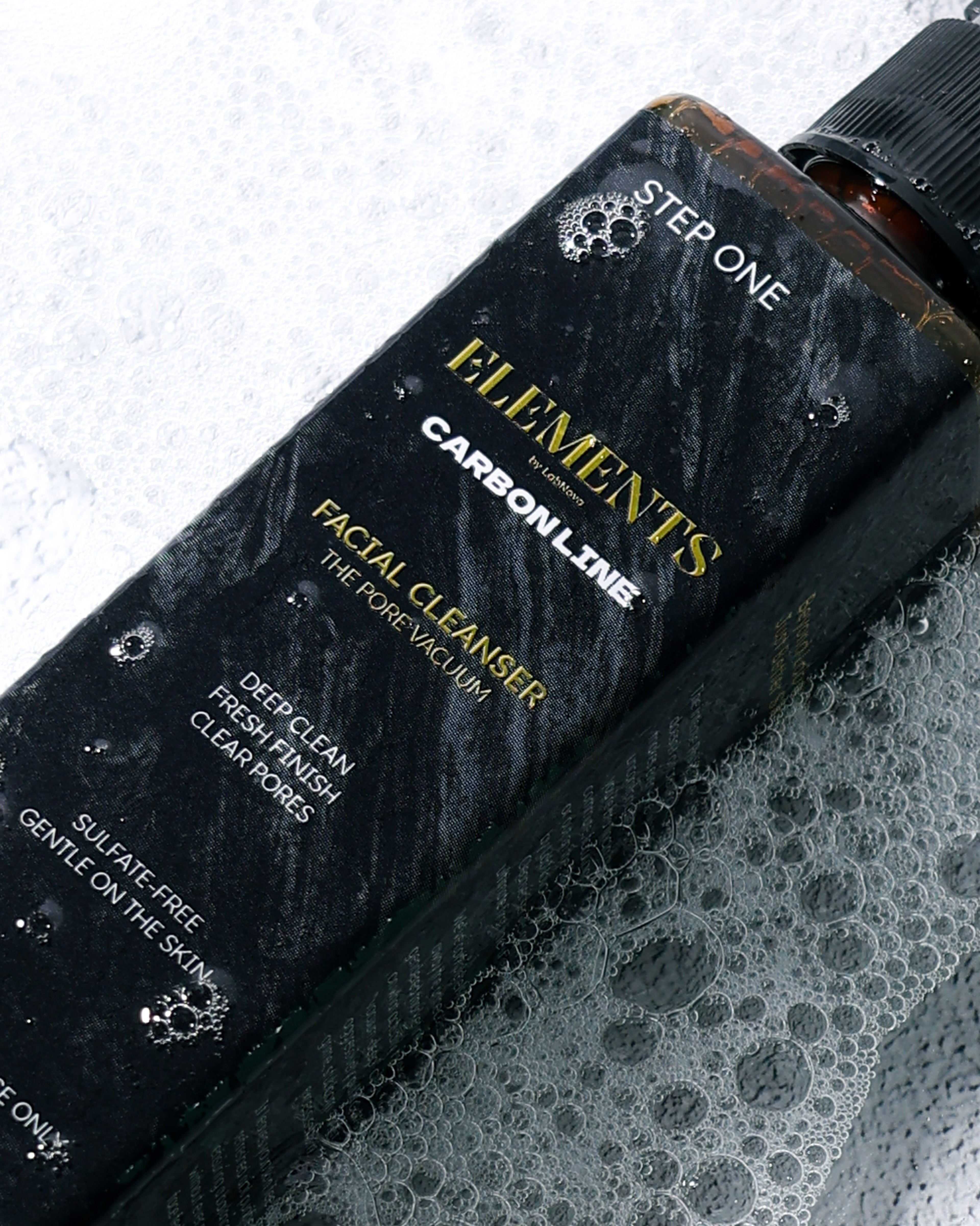 Black bottle labeled 'Elements' on a textured surface with bubbles.