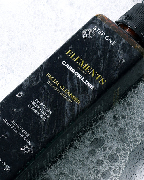 Black bottle labeled 'Elements' on a textured surface with bubbles.