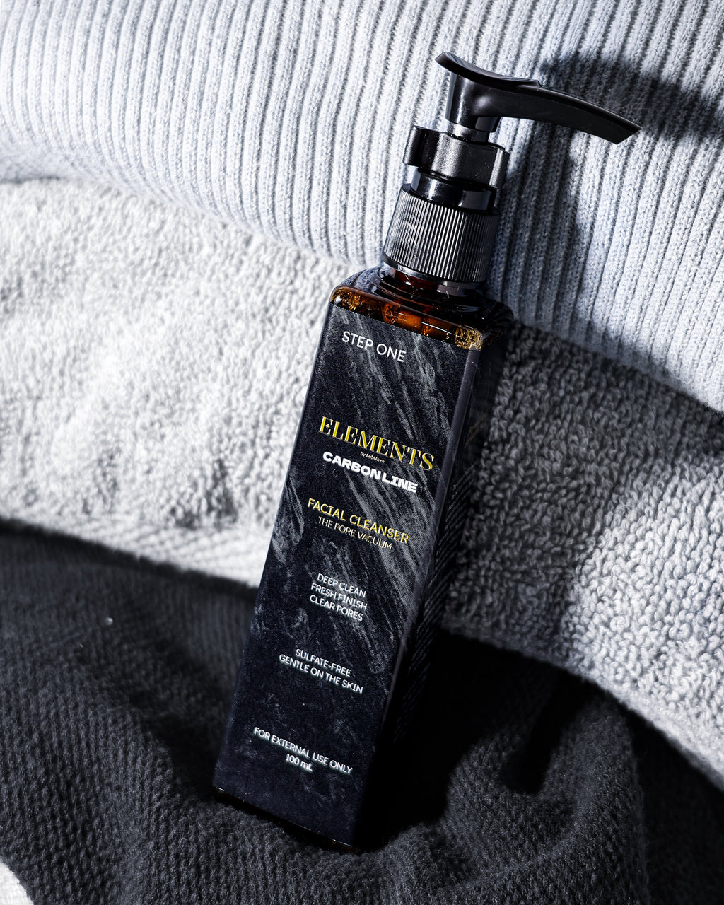 Facial cleanser bottle with pump on textured fabric background