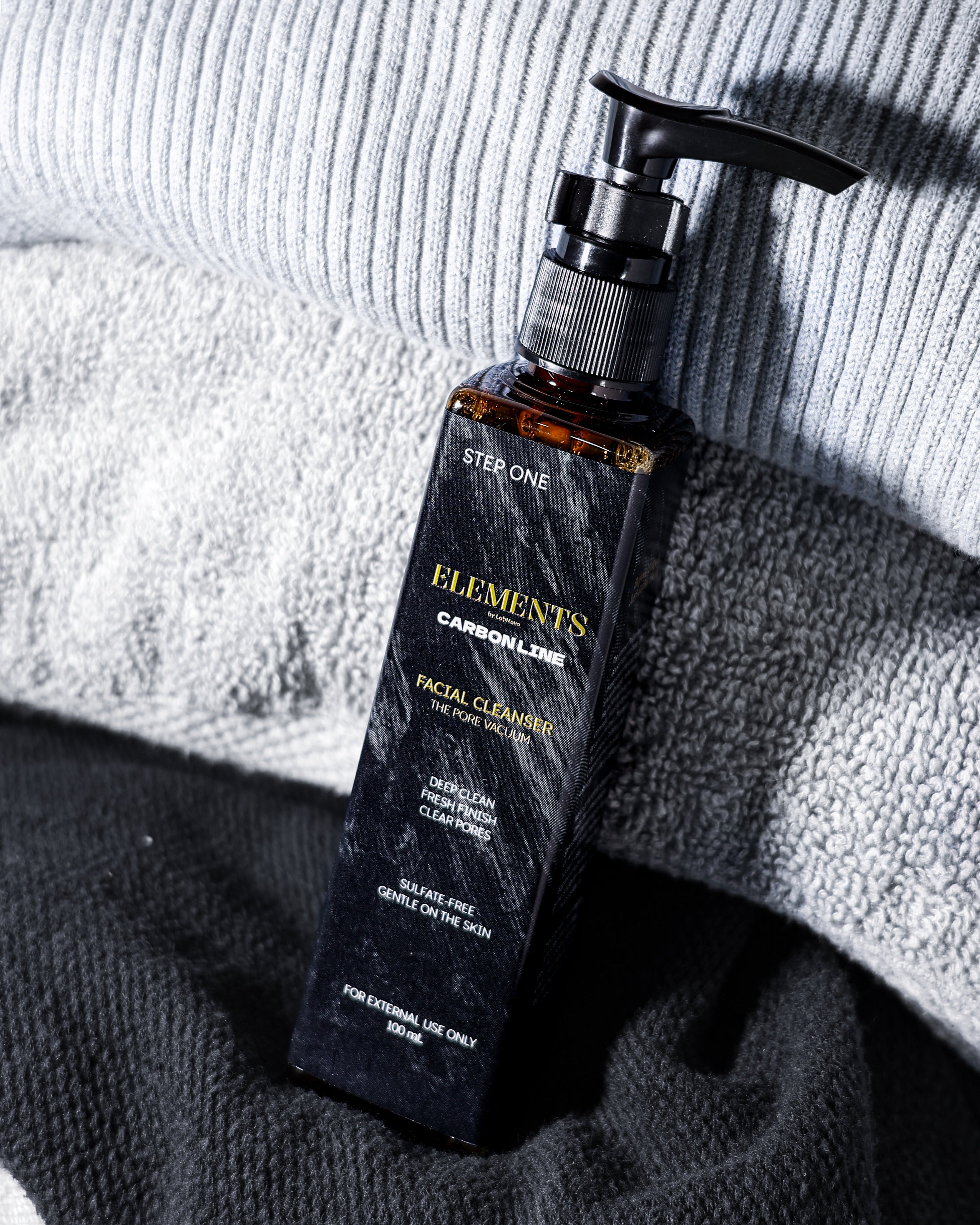 Facial cleanser bottle with pump on textured fabric background