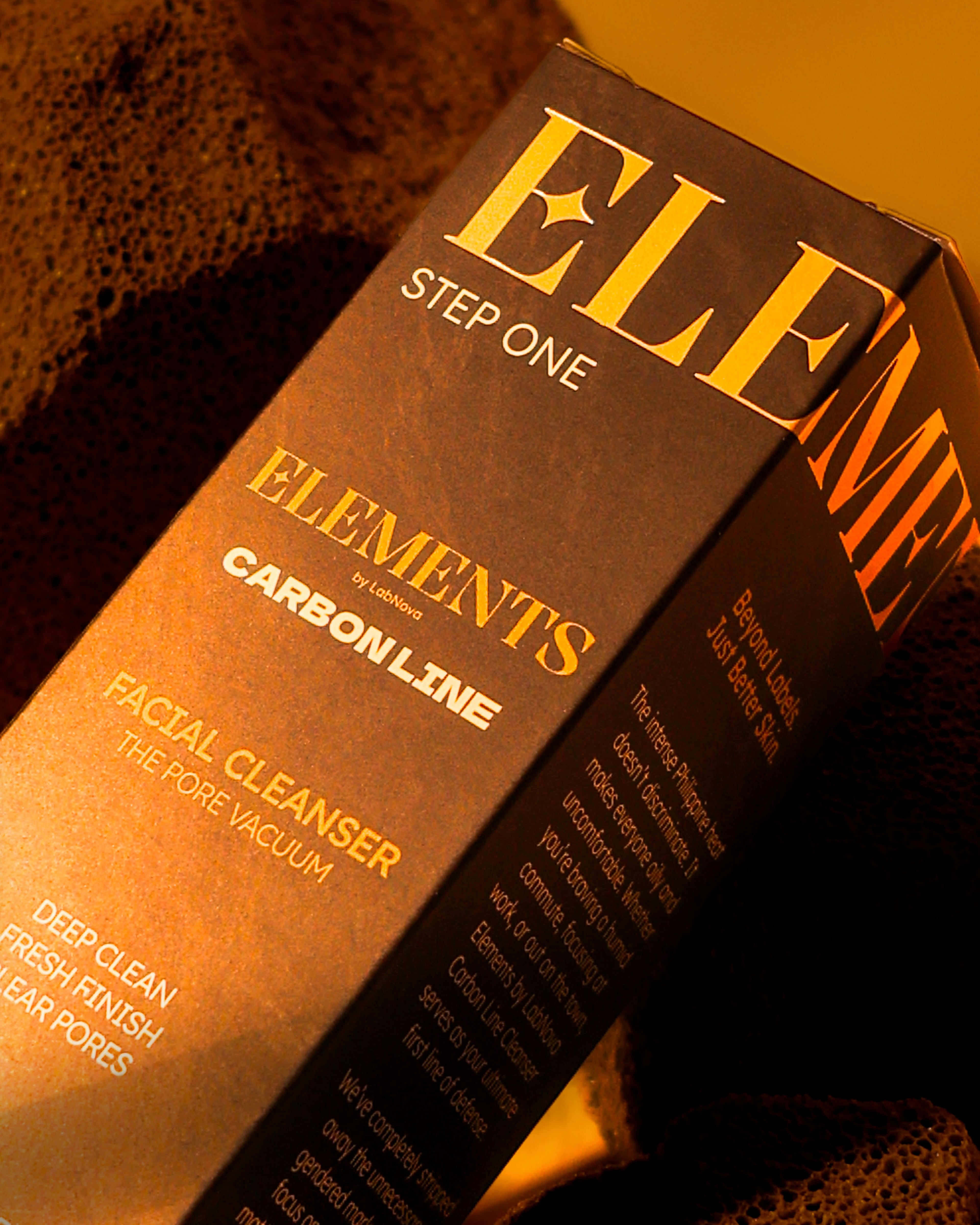 Close-up of a 'Elements' carbon line facial cleanser box with a brown background.