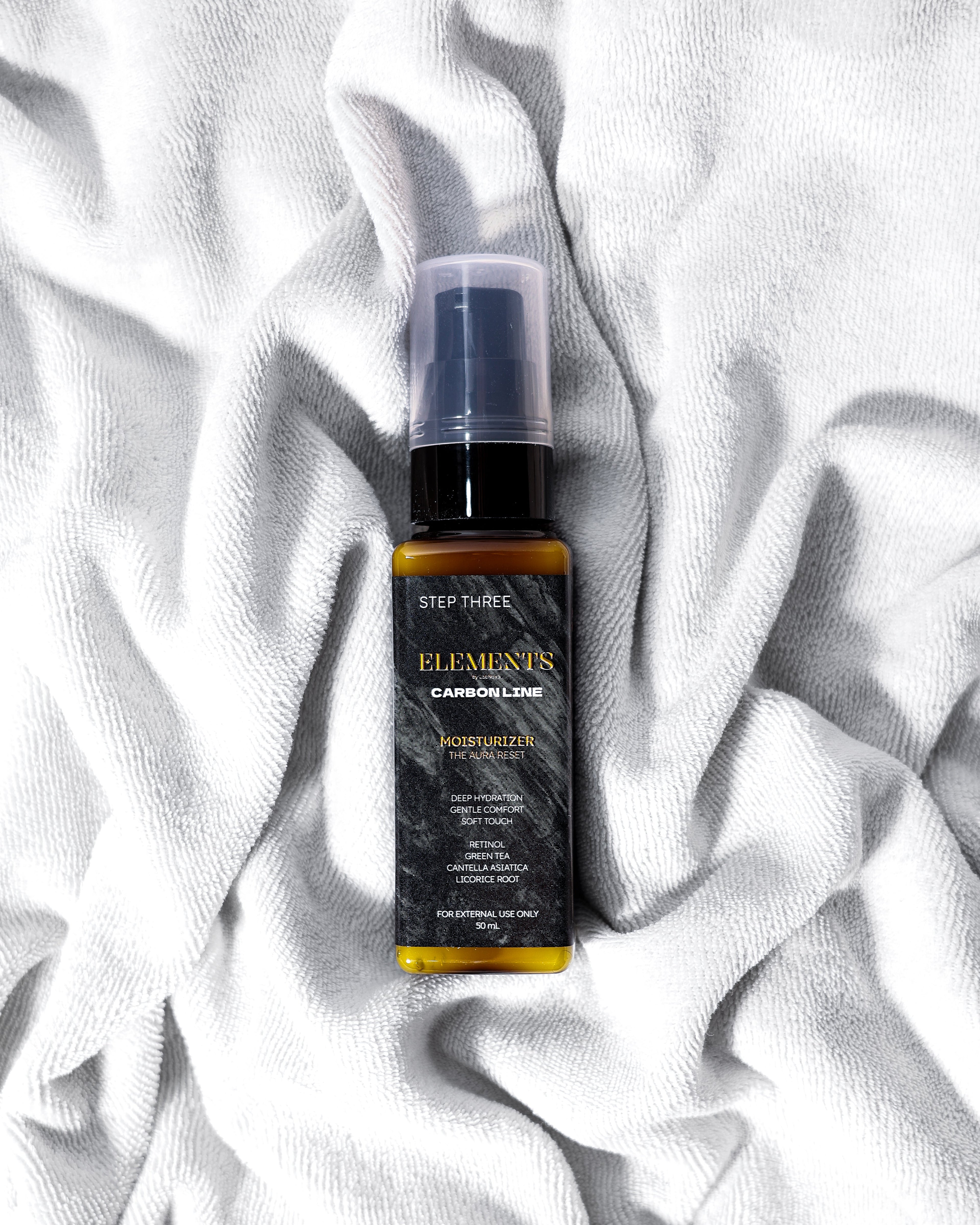 Skincare serum bottle labeled 'Elements' on a white textured fabric background