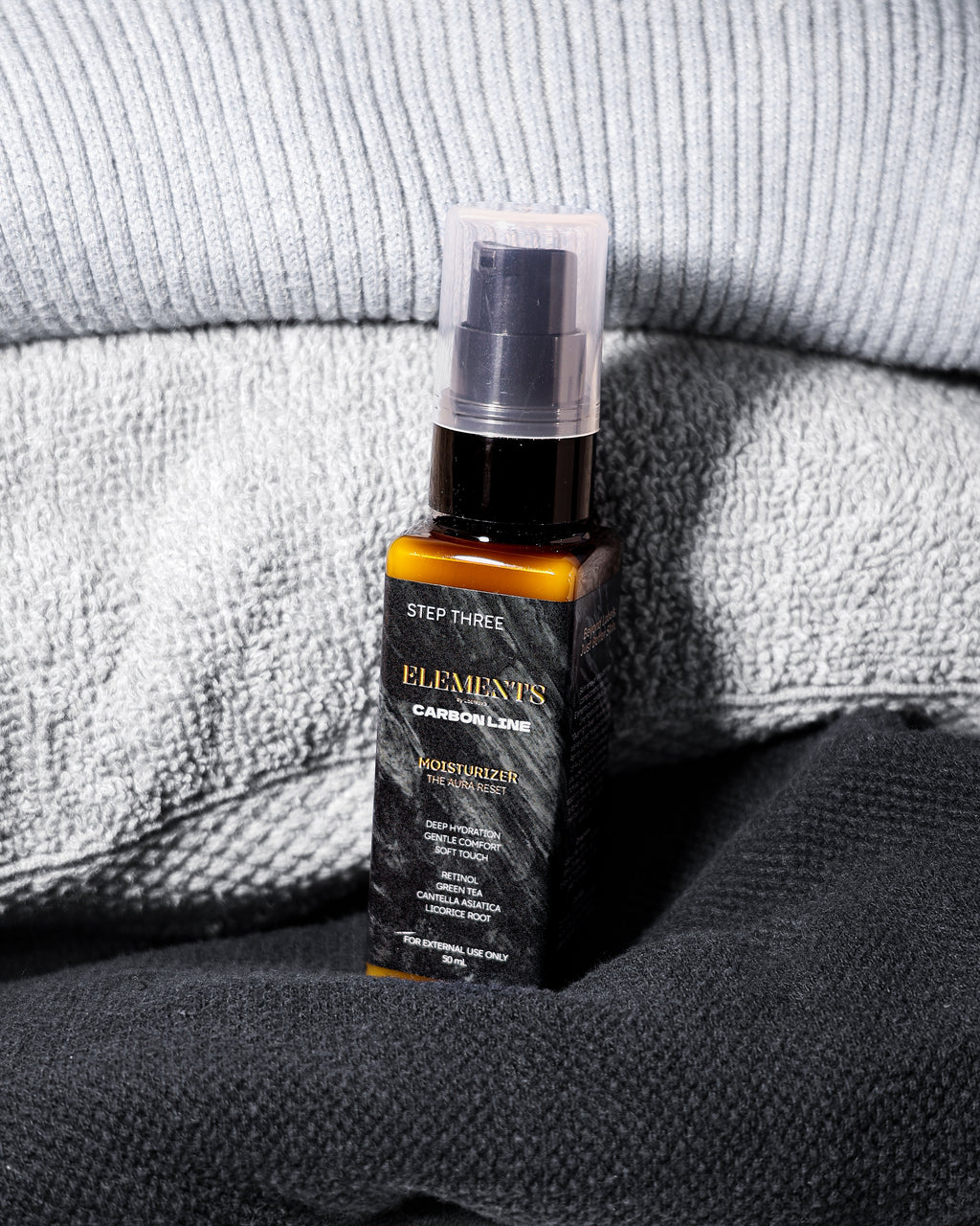 Bottle of 'Elements' skincare product on a textured fabric background