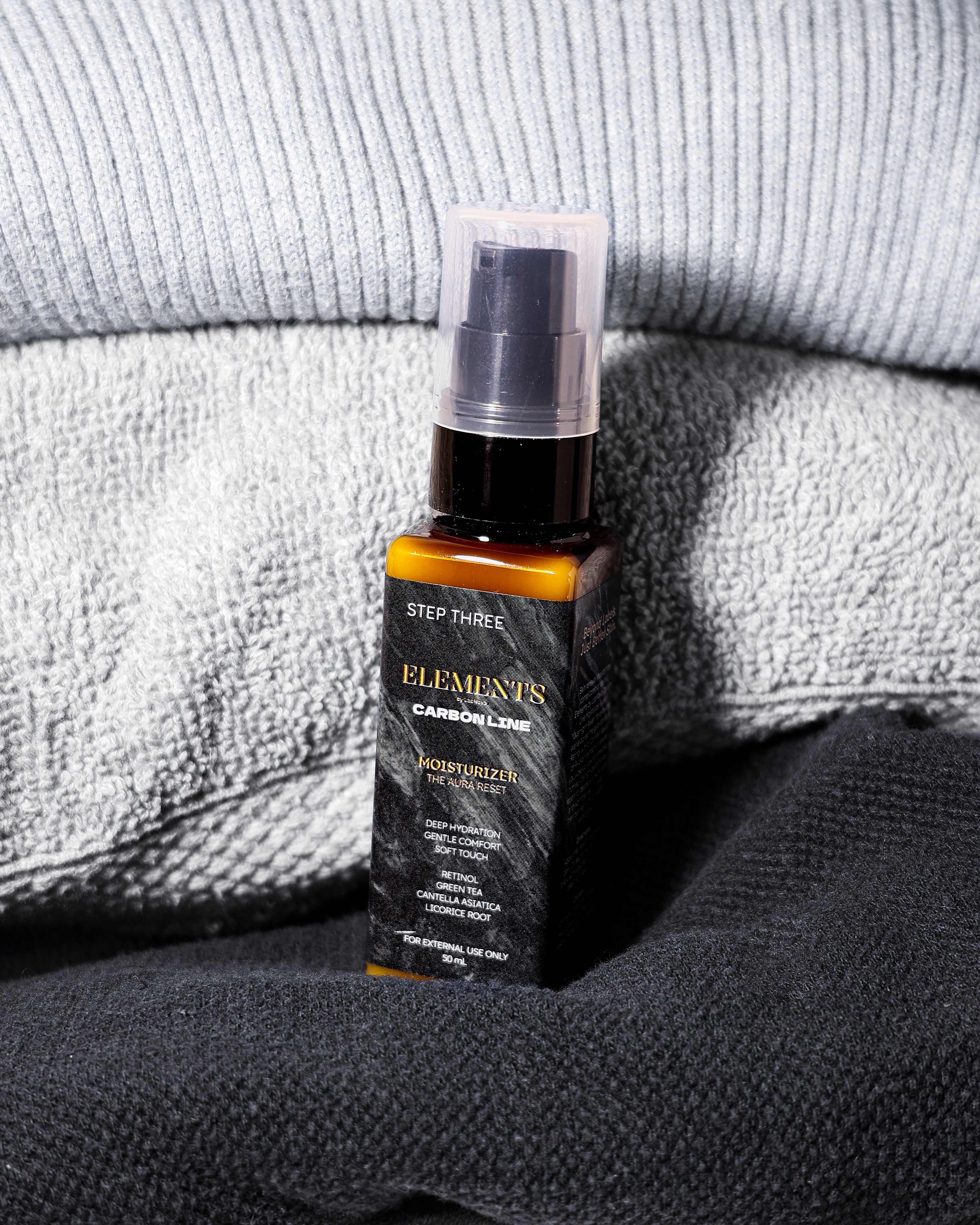 Bottle of 'Elements' skincare product on a textured fabric background
