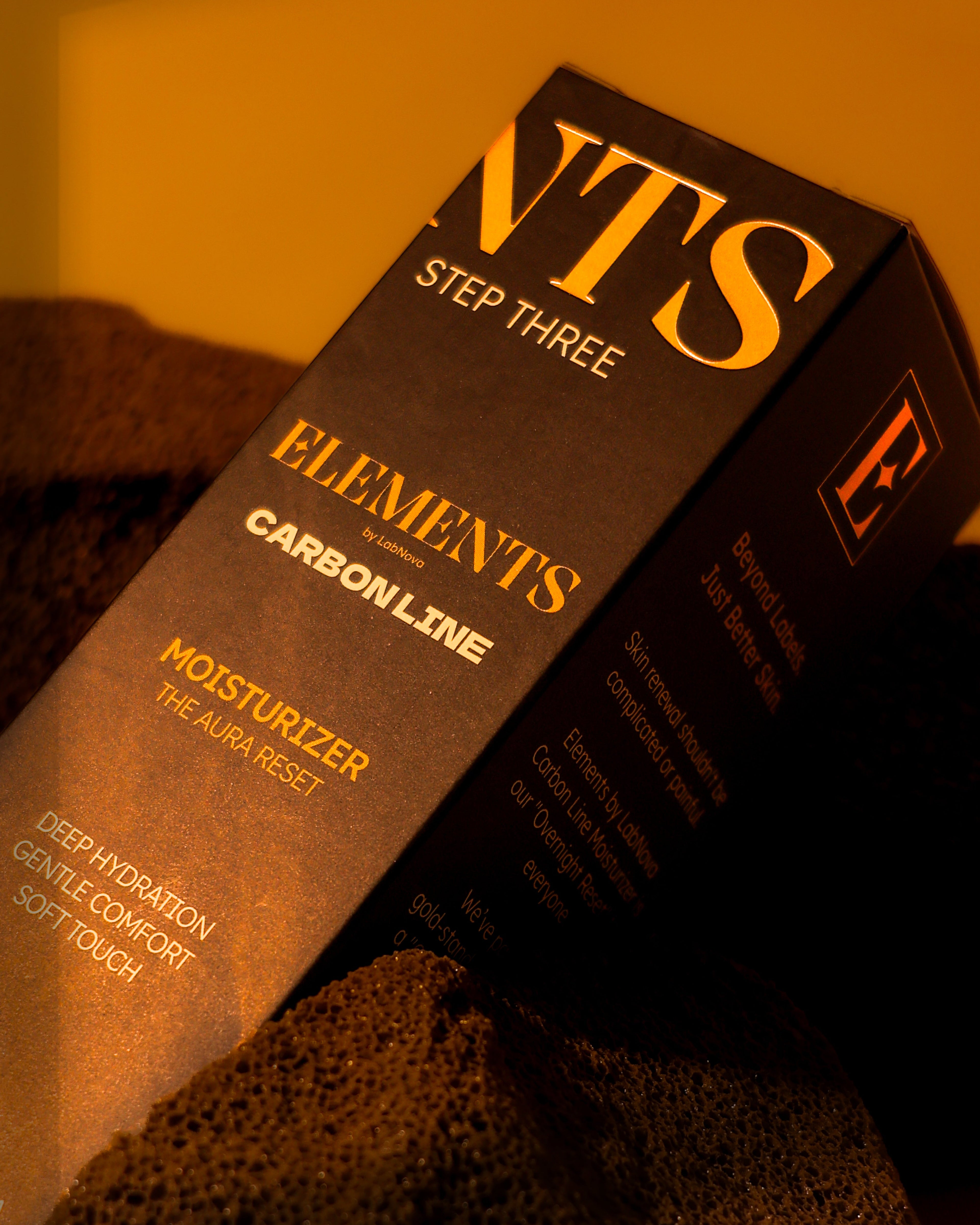 ELEMENTS skincare product packaging on a textured surface with warm lighting