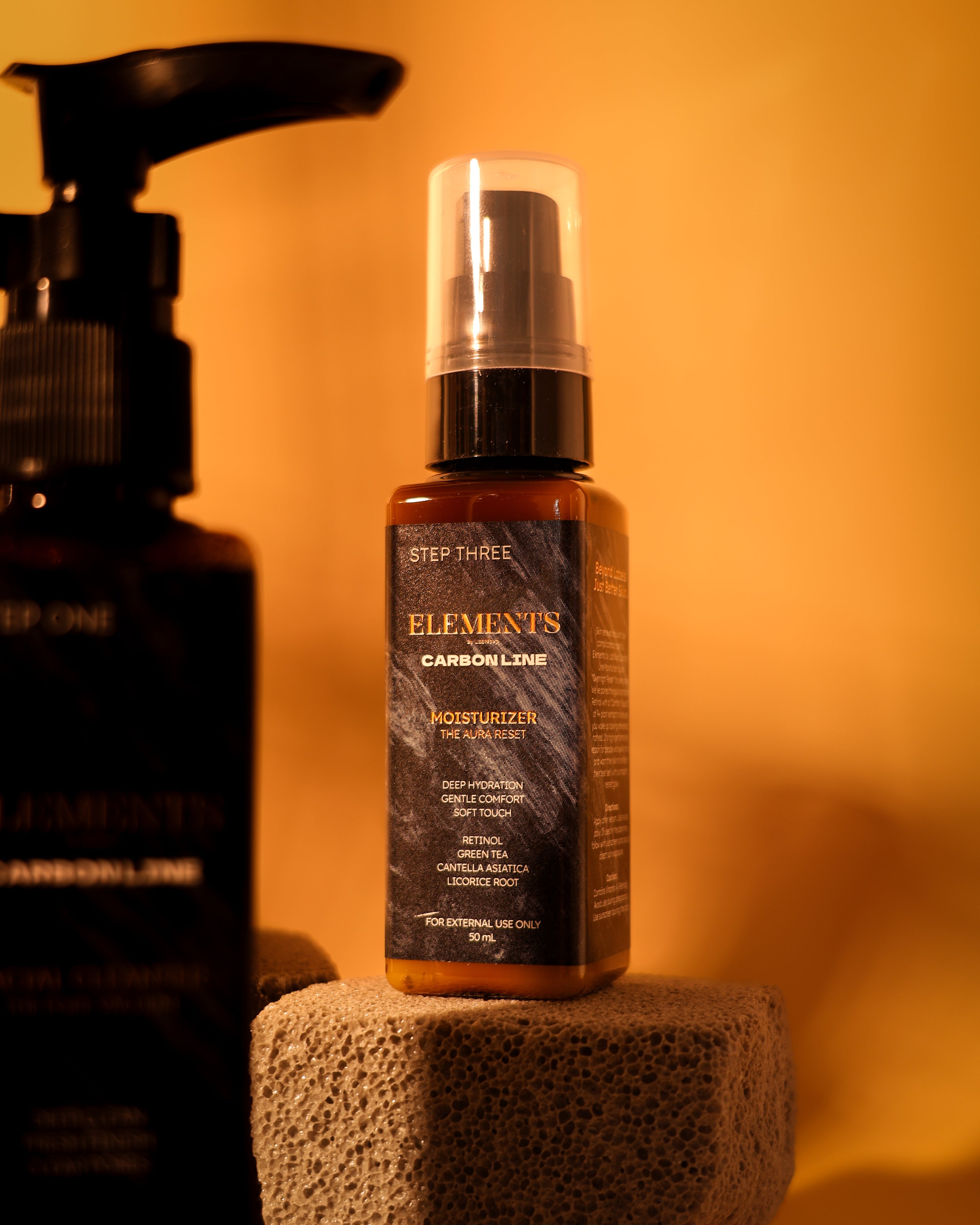 Skincare bottle labeled 'Elements' on a textured surface with a warm orange background