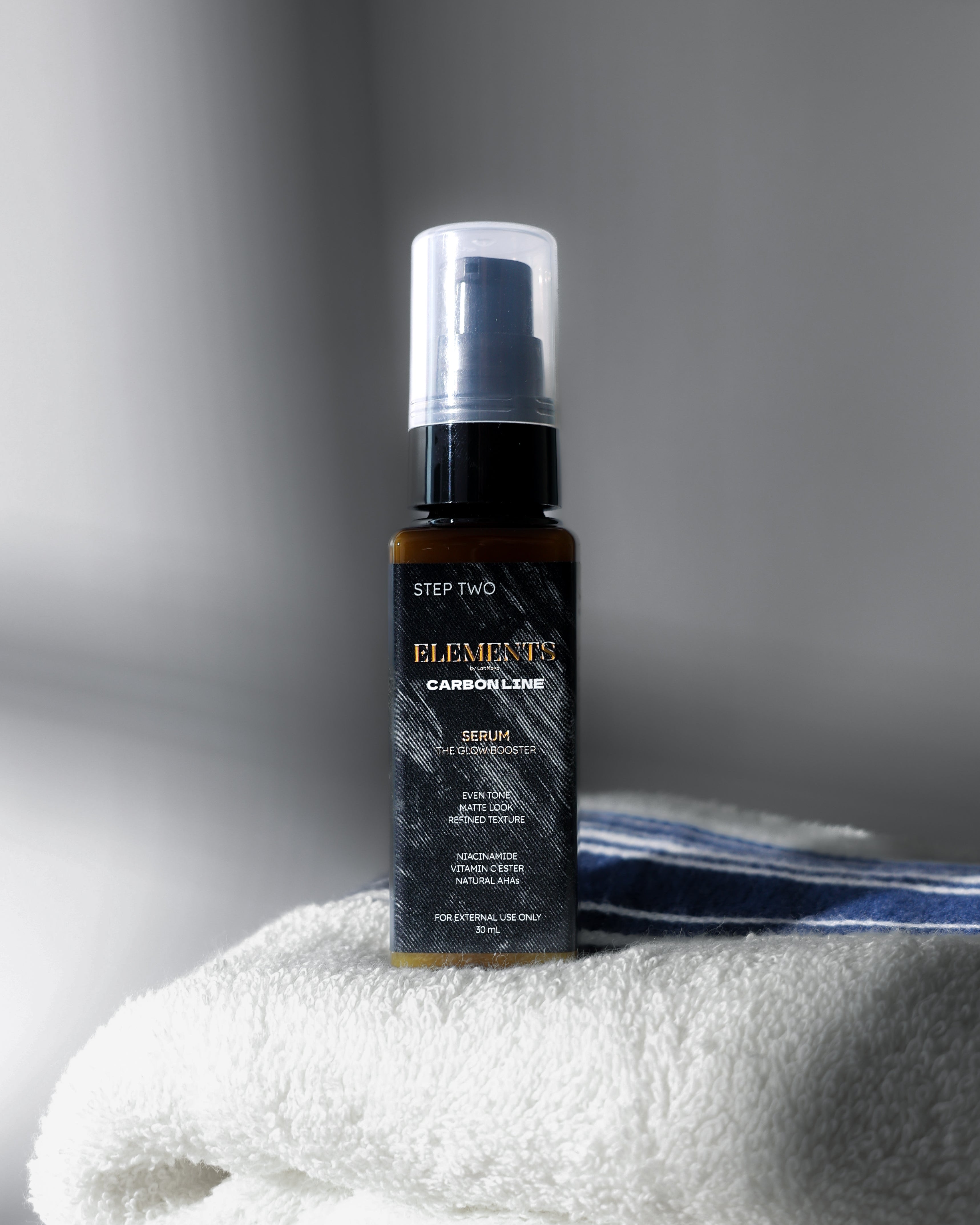 Bottle of 'Elemente Carbon Line' hair product on a white towel with a gray background