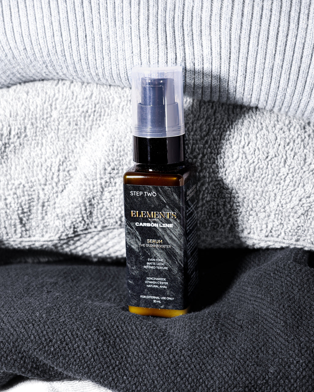 Skincare bottle labeled 'Elemente' on a textured surface with a towel in the background