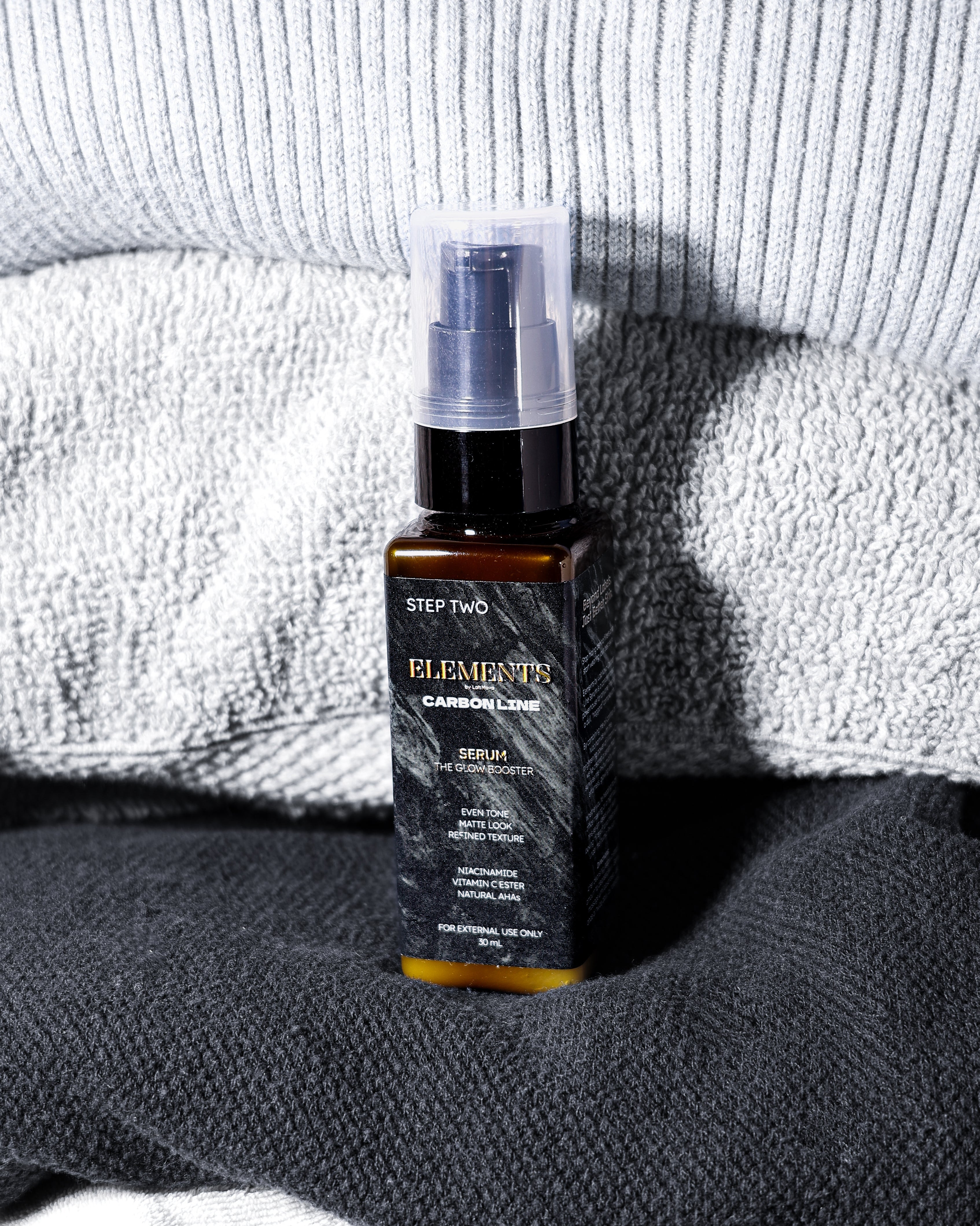 Skincare bottle labeled 'Elemente' on a textured surface with a towel in the background