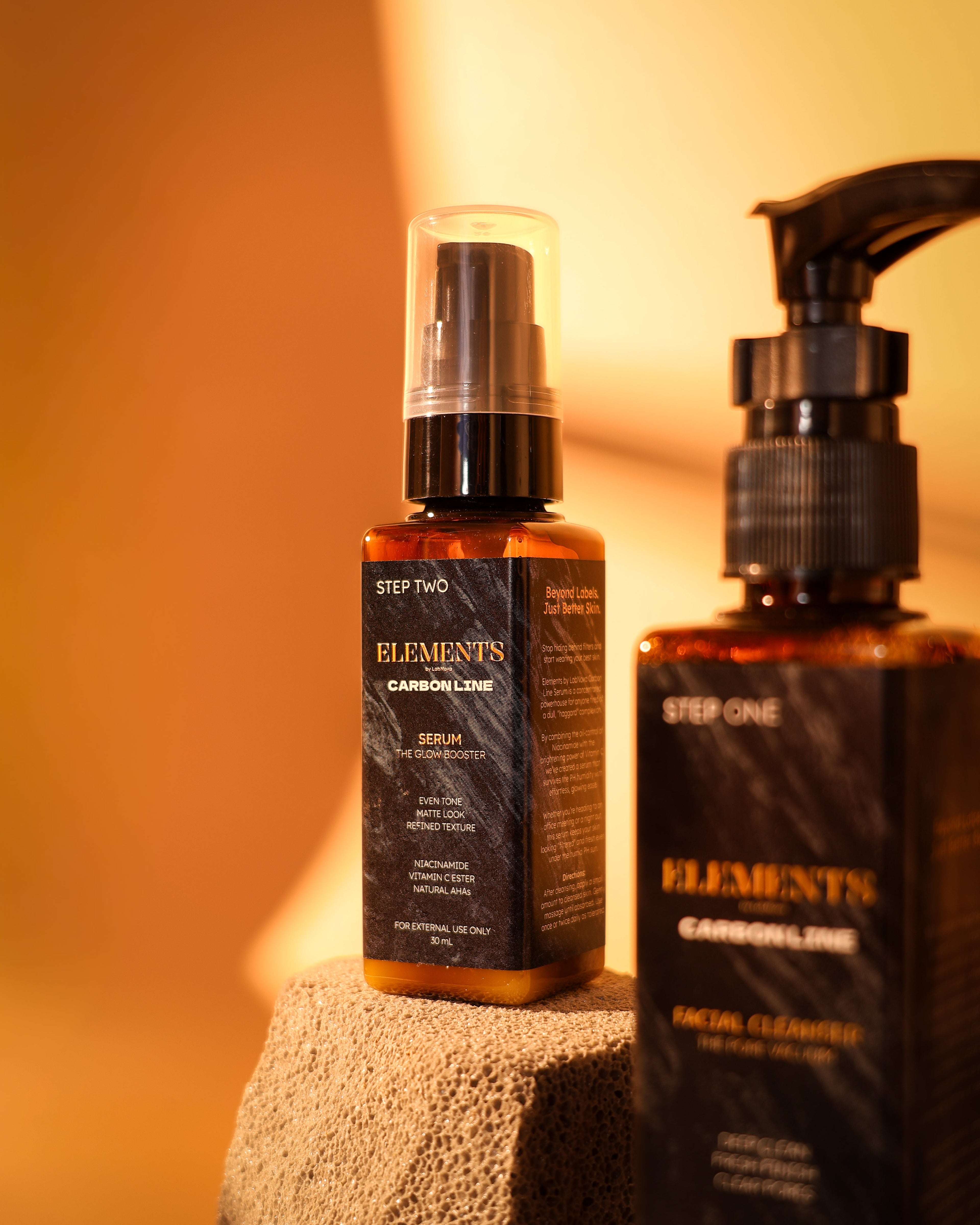 Two bottles of 'Elements' skincare products on a textured surface with a warm background.